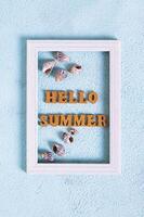 Hello summer text and seashells in photo frame on blue background top view and vertical view