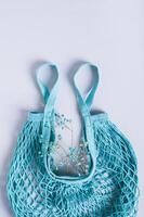 Concept of refusing plastic bags. String bag with dried flowers on a blue background photo