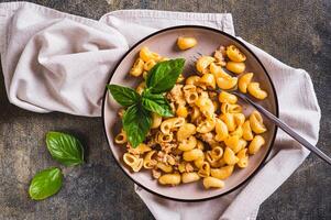 Close up of delicious pasta with minced meat and basil on a plate on the table top view photo