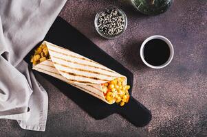 Mexican Burrito with corn, chicken and peppers in a tortilla on a slate board top view photo