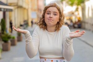 Confused woman feeling embarrassed about ambiguous question having doubts no idea in city street photo