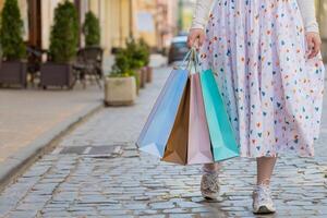 Anonymous woman shopaholic consumer after shopping sale with colorful bags with gifts outdoors city photo