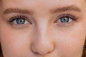 Extreme close-up macro portrait of young smiling redhead face, pretty woman's eyes looking at camera photo