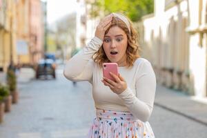 Happy redhead girl use smartphone celebrating win good message news lottery jackpot victory outdoors photo