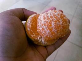 cerca arriba de pillado Mandarina en el mano foto