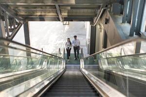 Two professionals in conversation while riding an escalator photo