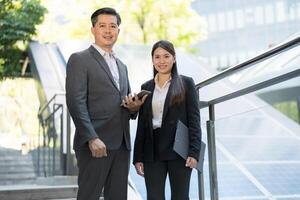 Two corporate professionals in formal attire standing confidently outside a modern office building photo