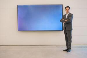 Confident businessman standing by digital display photo