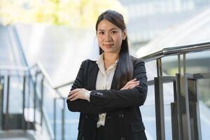 Professional woman with a cheerful smile standing by a staircase outdoors photo