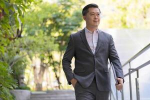 Professional male executive walking up stairs in an urban environment during the daytime photo