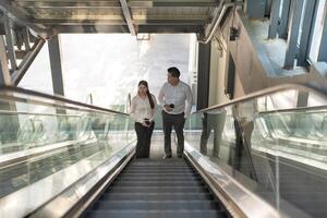 Two professionals in conversation while riding an escalator photo
