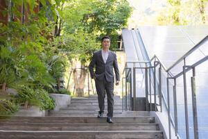 Professional male executive walking up stairs in an urban environment during the daytime photo