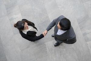 Top view of two professionals in suits shaking hands in a modern office building photo