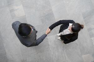 Top view of two professionals in suits shaking hands in a modern office building photo