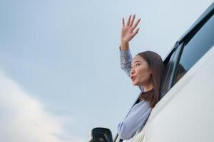 Joyful young woman waving from car window photo