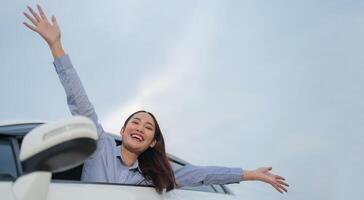 Joyful young woman waving from car window photo