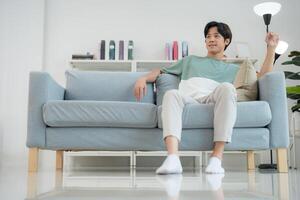 Young man relaxing comfortably on a modern sofa at home photo