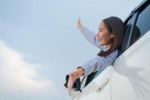 Joyful young woman waving from car window photo