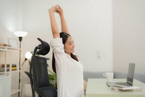 Young woman stretching while working from home photo