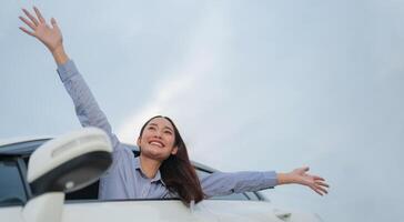 Joyful young woman waving from car window photo