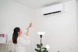 Young woman controlling smart air conditioning system at home photo