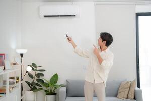 Young man using remote to adjust air conditioning at home photo