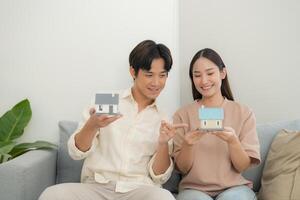 Young couple holding a model house in living room photo