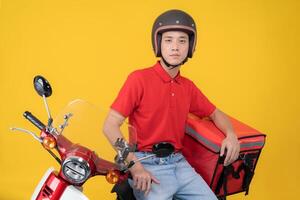 Happy delivery rider with motorbike on yellow background photo