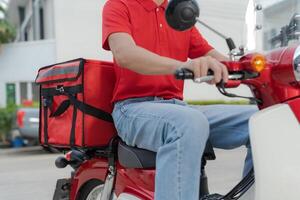 Delivery rider on red motorbike with insulated food box parked outdoors photo