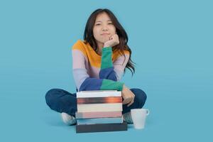 Woman sitting on the floor with a stack of books and a cup photo