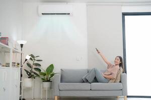 joven mujer disfrutando aire acondicionamiento a hogar foto