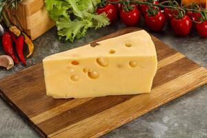 Swiss Maasdam cheese triangle over board photo