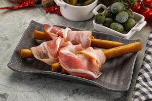 Antipasti - Grissini with pork bacon photo