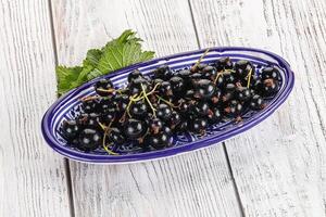 Juicy black currant berries in the bowl photo