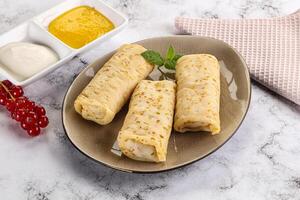 Homemade stuffed pancakes with honey and cream sour photo