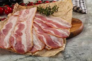 Sliced pork bacon over board photo