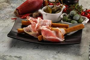 Antipasti - Grissini with pork bacon photo