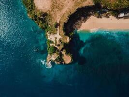 Aerial view of beach with rock and turquoise ocean in Bali. Top view photo