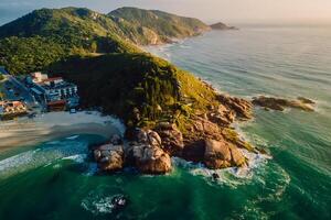 Beach with scenic coastline and ocean with waves at warm sunrise in Brazil. Aerial view photo