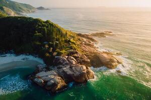 Coastline with rocks and ocean with waves at warm sunrise in Brazil. Aerial view photo