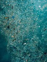 Ocean water and plastic trash in Bali. Aerial view of pollution by plastic rubbish photo