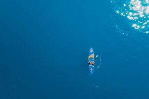 May 15, 2021. Anapa, Russia. Woman on stand up paddle board at blue sea. Woman paddle on sup board in sea. Aerial view photo