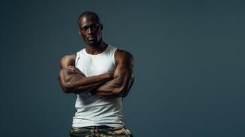 Man in camo pants and white tank top stands with arms crossed photo