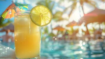 Glass of citrus cocktail with lime slice and umbrella on poolside table photo