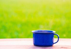 pava, azul esmalte, y café tazas en un antiguo de madera piso, borroso antecedentes de arroz campos a amanecer. foto