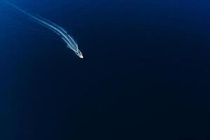 Motor boat is sailing in blue deep sea. Aerial view photo