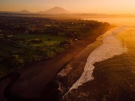 Aerial view of beach with Agung volcano, warm sunrise or sunset tones and ocean in Bali photo