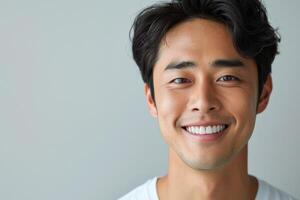 Young korean man smiling and looking at camera on gray background photo