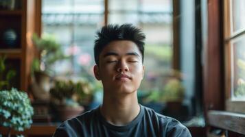 Jaw dropped in awe, young man sitting by plant, eyes closed, smiling photo