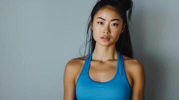 A woman in an electric blue sports bra stands by a gray wall photo